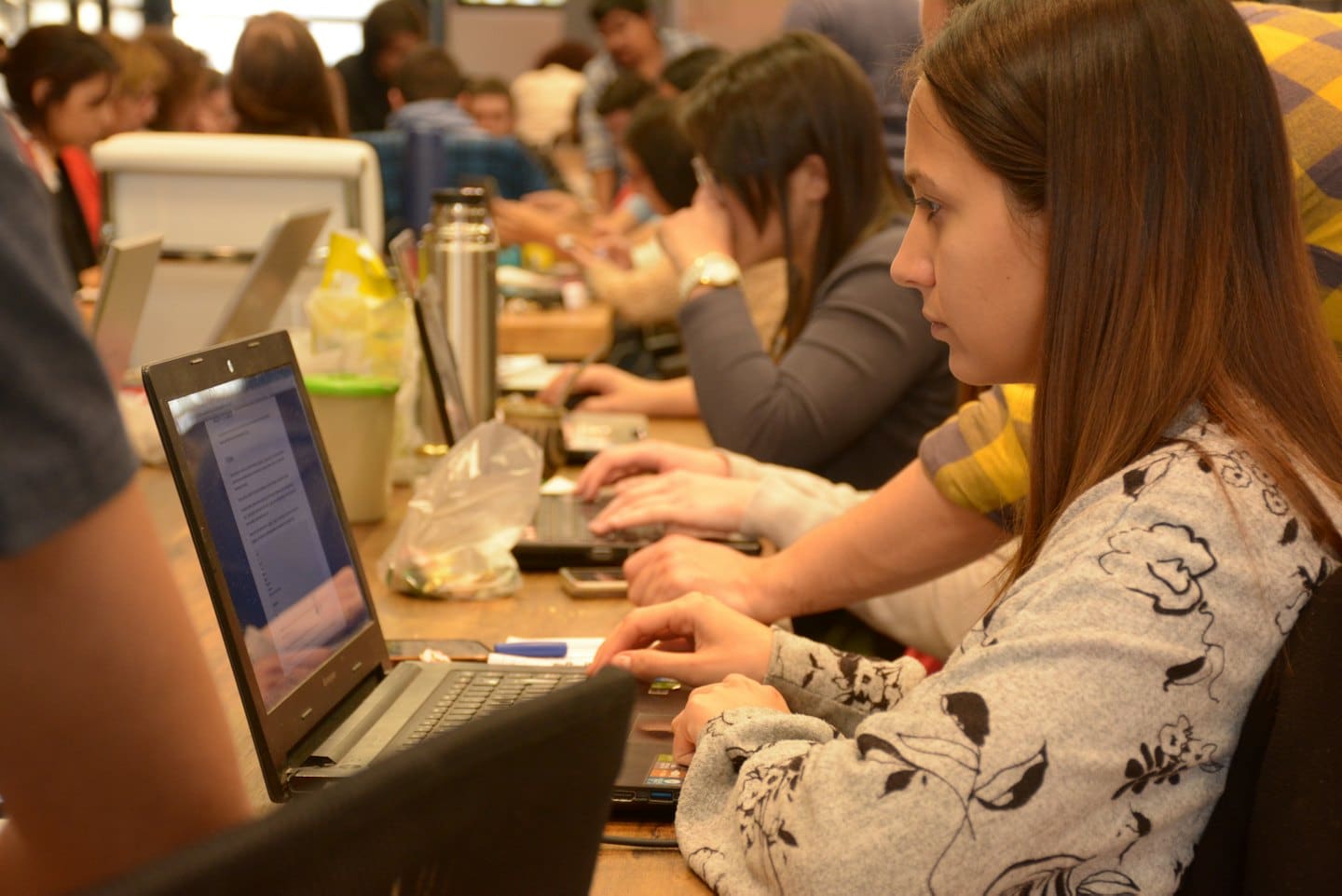 A group of professionals working on laptops at wooden desks.